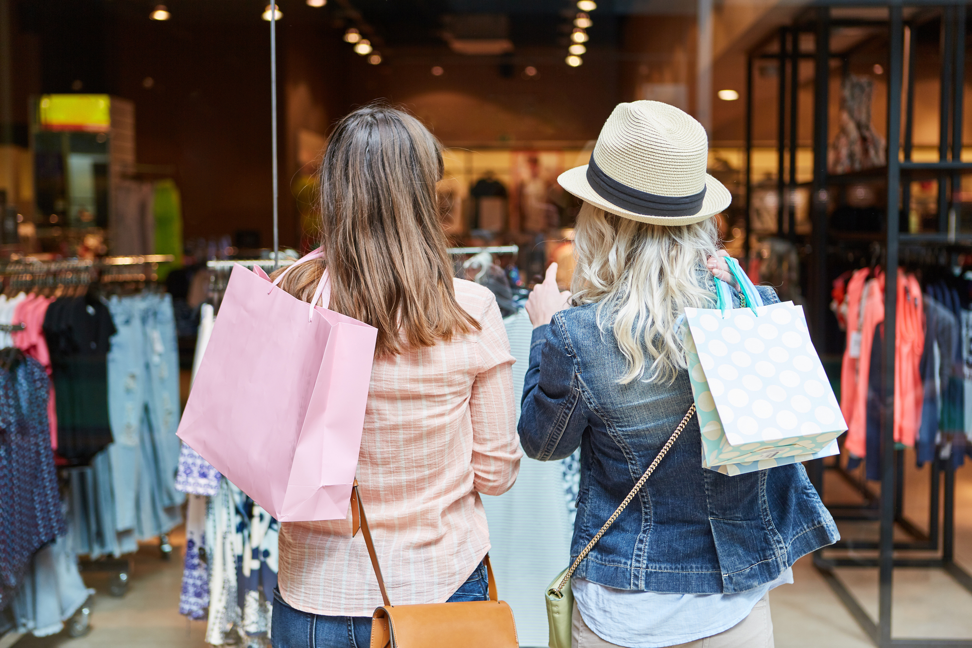 Two women browsing clothing racks in a retail store
